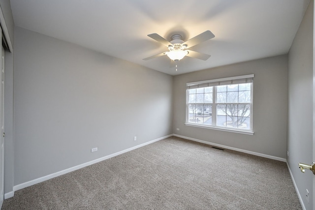 spare room featuring a ceiling fan, baseboards, visible vents, and carpet flooring