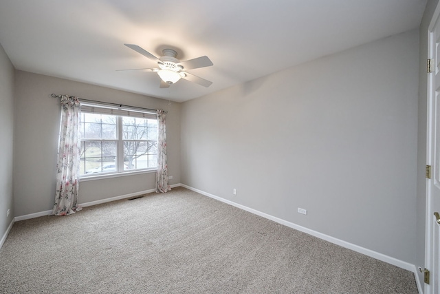 empty room with carpet floors, visible vents, baseboards, and a ceiling fan