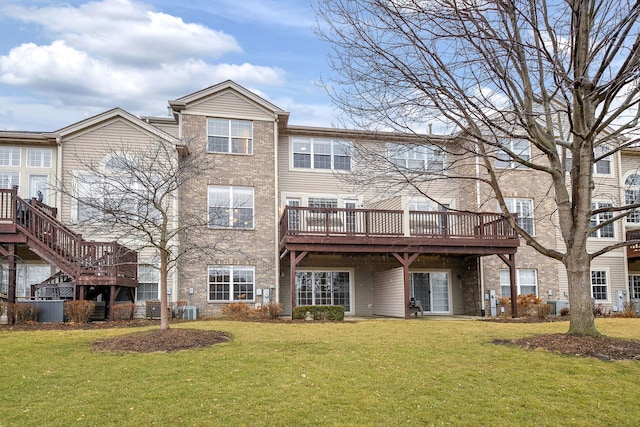 back of property with central AC, brick siding, a lawn, and a wooden deck