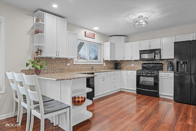 kitchen with open shelves, dark wood-type flooring, white cabinetry, light stone countertops, and black appliances