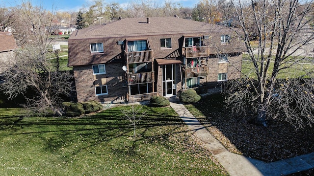 rear view of property with a yard and a balcony