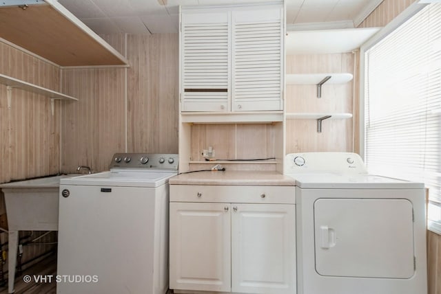 laundry room featuring wooden walls, cabinet space, and washer and clothes dryer