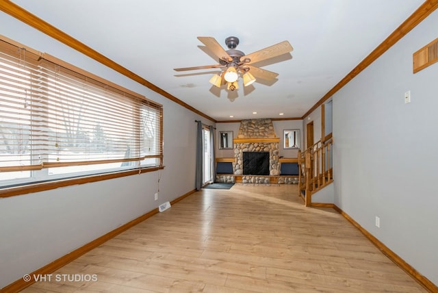 unfurnished living room with baseboards, a stone fireplace, visible vents, and light wood-style floors