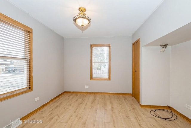 unfurnished room with light wood-type flooring, visible vents, and baseboards