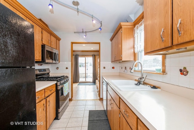 kitchen featuring light tile patterned floors, tasteful backsplash, stainless steel appliances, light countertops, and a sink