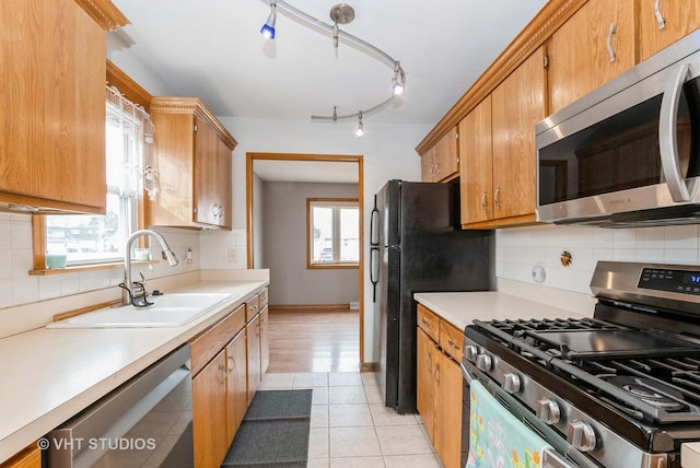 kitchen featuring light tile patterned floors, a sink, light countertops, appliances with stainless steel finishes, and decorative backsplash