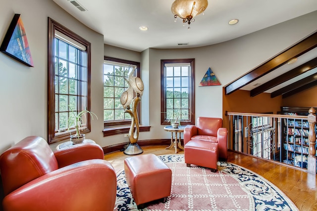 living area featuring beamed ceiling and wood-type flooring