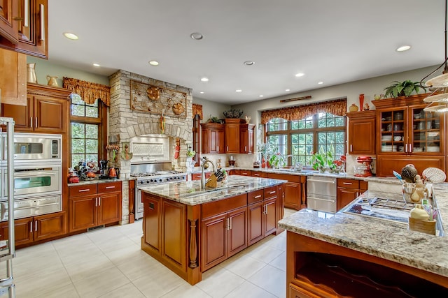 kitchen featuring appliances with stainless steel finishes, sink, light stone countertops, and a center island