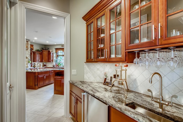 bar featuring light tile patterned flooring, sink, light stone counters, and decorative backsplash