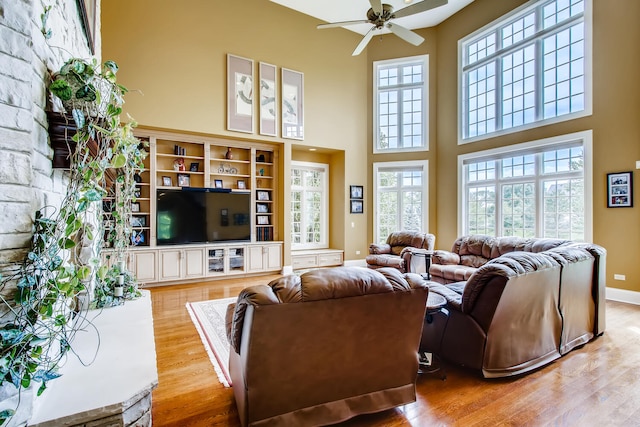 living room featuring a high ceiling, ceiling fan, and light hardwood / wood-style flooring