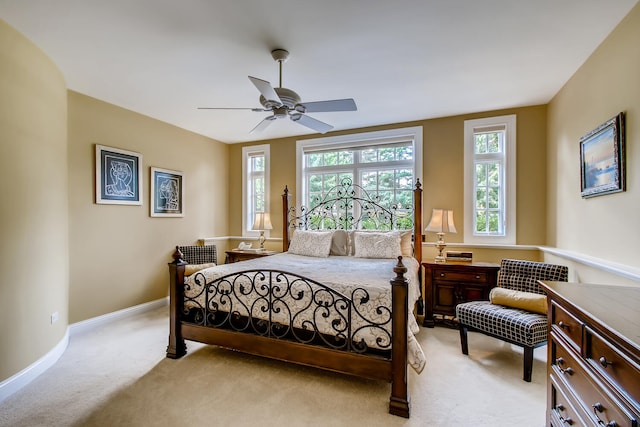 bedroom featuring ceiling fan, multiple windows, and light colored carpet