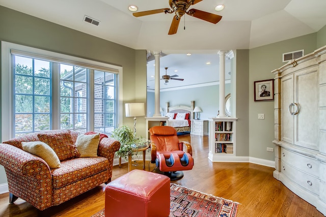 sitting room with ceiling fan, decorative columns, and wood-type flooring