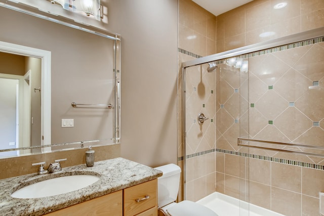 bathroom featuring toilet, vanity, and walk in shower