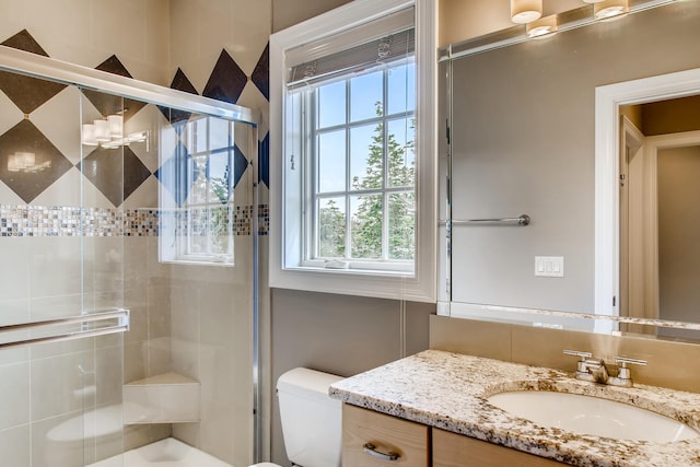 bathroom with toilet, a shower with door, and vanity