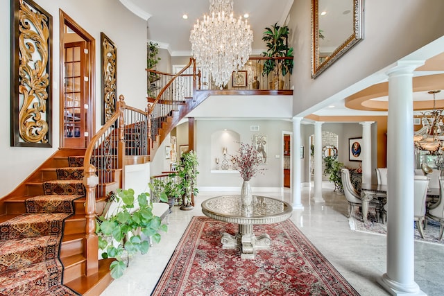 entrance foyer with ornamental molding, a chandelier, decorative columns, and a towering ceiling