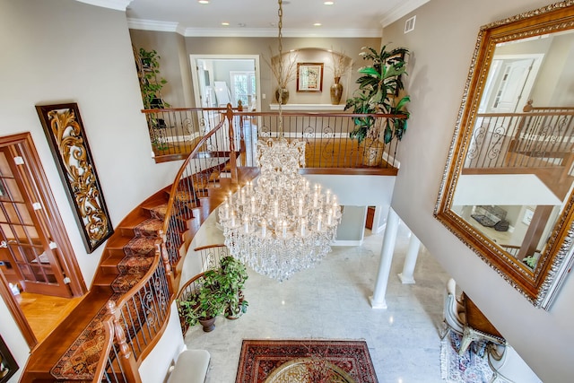 stairs featuring decorative columns, ornamental molding, and a chandelier