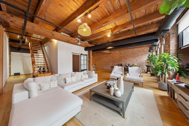 living area featuring a barn door, wood ceiling, brick wall, wood finished floors, and stairs