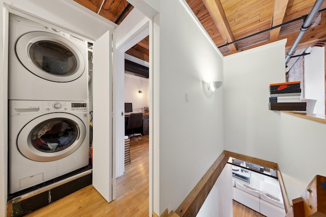 clothes washing area featuring laundry area, stacked washing maching and dryer, wood finished floors, and wooden ceiling