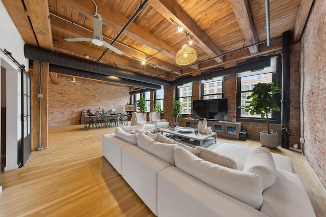 living area with rail lighting, a barn door, brick wall, wood finished floors, and wooden ceiling