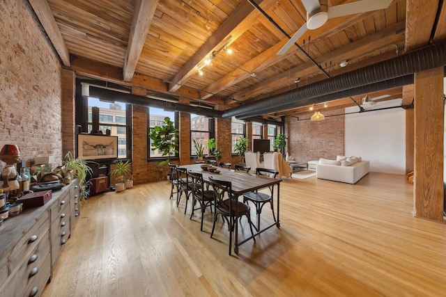 dining area featuring track lighting, wooden ceiling, brick wall, light wood-style floors, and beam ceiling