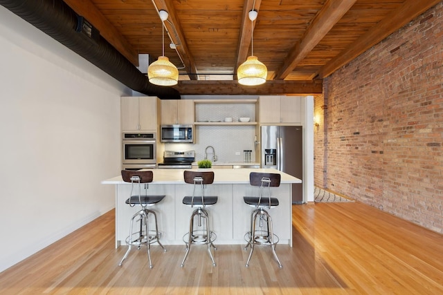 kitchen featuring appliances with stainless steel finishes, brick wall, light countertops, and light wood finished floors