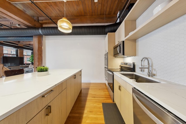 kitchen featuring appliances with stainless steel finishes, decorative light fixtures, a sink, light wood-style floors, and beam ceiling