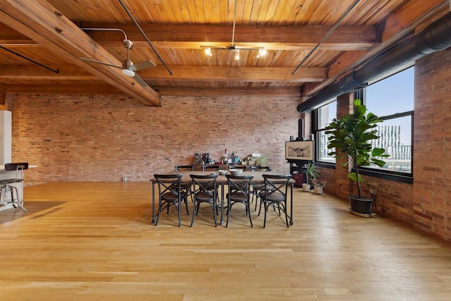 unfurnished dining area featuring ceiling fan, brick wall, wood finished floors, wood ceiling, and beamed ceiling