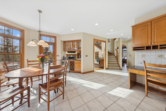 dining room featuring arched walkways, baseboards, stairway, light tile patterned flooring, and recessed lighting