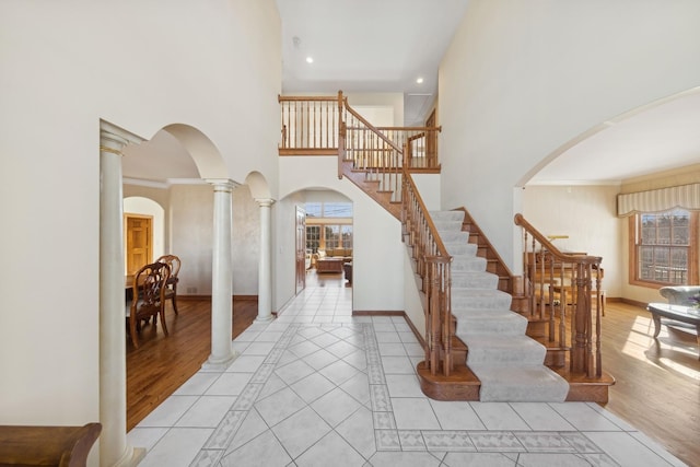 entryway featuring arched walkways, a healthy amount of sunlight, light wood finished floors, and ornate columns