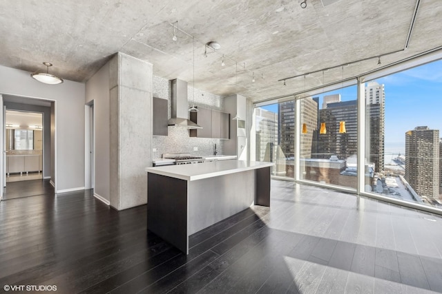 kitchen featuring wall chimney exhaust hood, modern cabinets, decorative light fixtures, a view of city, and light countertops