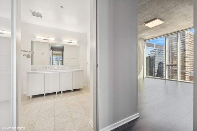 bathroom featuring a view of city, floor to ceiling windows, vanity, and baseboards