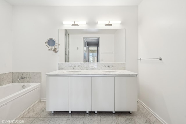 full bathroom with marble finish floor, a garden tub, a sink, and double vanity