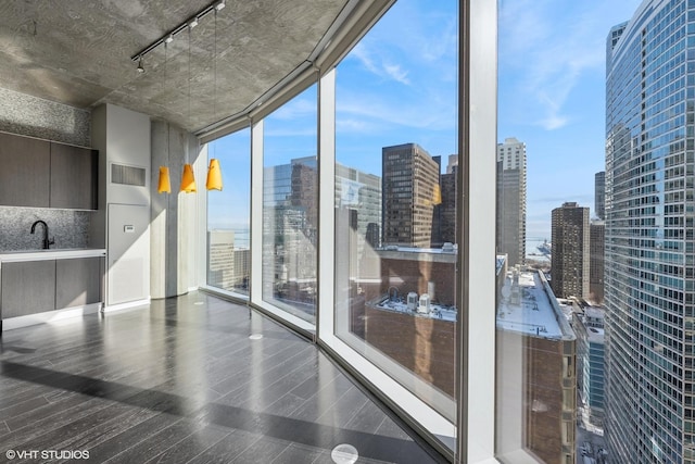 interior space featuring a wall of windows, a view of city, rail lighting, and dark wood finished floors