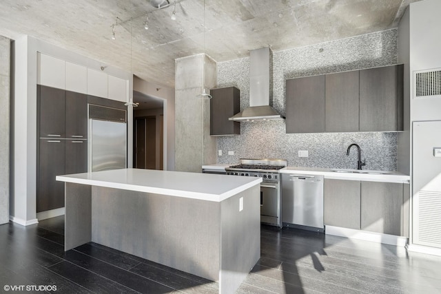 kitchen with a sink, light countertops, wall chimney range hood, high end appliances, and modern cabinets