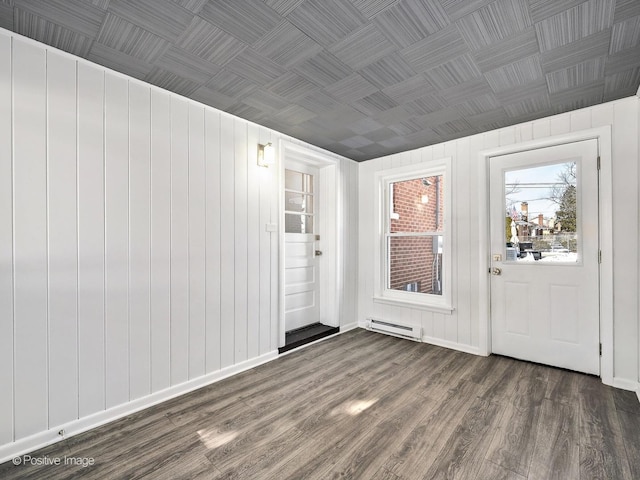 interior space featuring baseboard heating, dark wood finished floors, an ornate ceiling, and baseboards