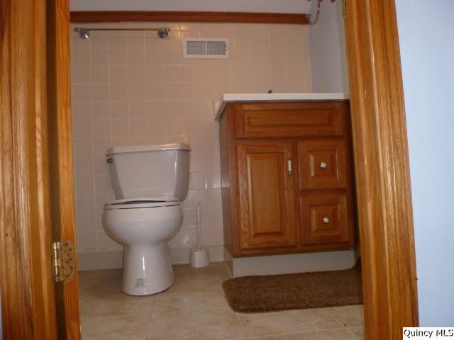 bathroom featuring tile walls, toilet, vanity, and tile patterned flooring