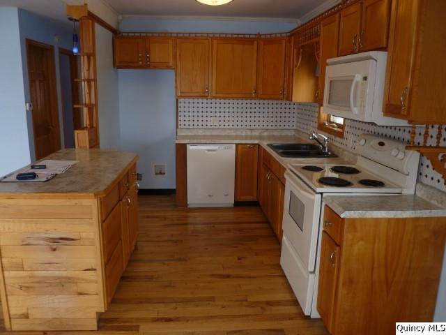 kitchen with white appliances, sink, backsplash, light hardwood / wood-style floors, and crown molding