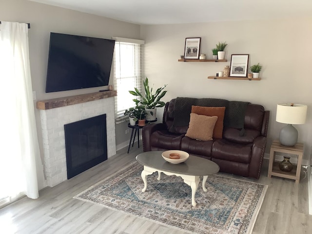 living room featuring light wood-type flooring and a brick fireplace