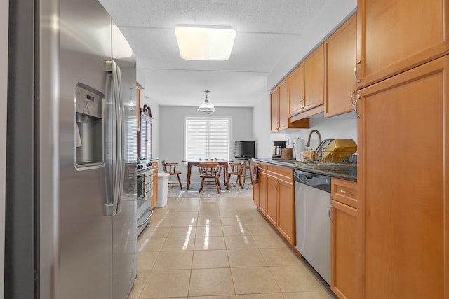 kitchen featuring stainless steel appliances, hanging light fixtures, sink, light tile patterned floors, and a textured ceiling