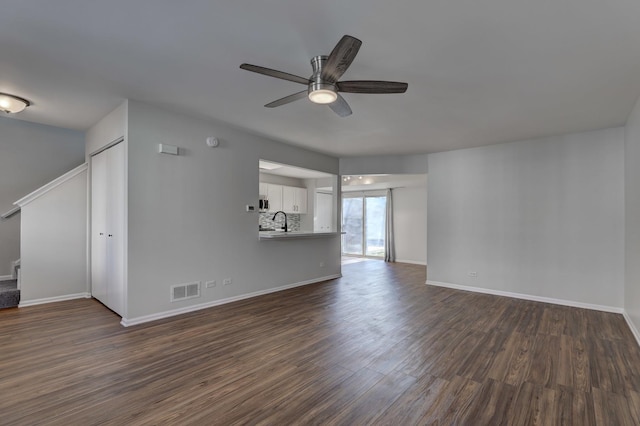 unfurnished living room with sink, ceiling fan, and dark wood-type flooring