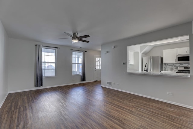 unfurnished living room with dark hardwood / wood-style flooring and ceiling fan