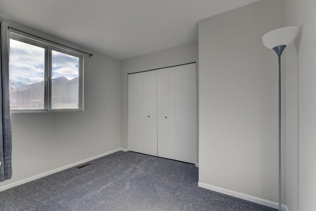 unfurnished bedroom with a closet and dark colored carpet