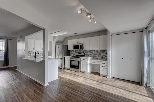 kitchen with appliances with stainless steel finishes, light hardwood / wood-style flooring, white cabinetry, and kitchen peninsula