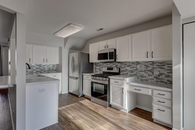 kitchen with appliances with stainless steel finishes, light hardwood / wood-style flooring, white cabinets, decorative backsplash, and sink