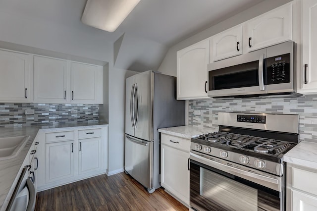 kitchen with appliances with stainless steel finishes, dark hardwood / wood-style flooring, white cabinets, and backsplash