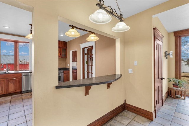 kitchen featuring dark countertops, a wealth of natural light, range, stainless steel dishwasher, and a sink