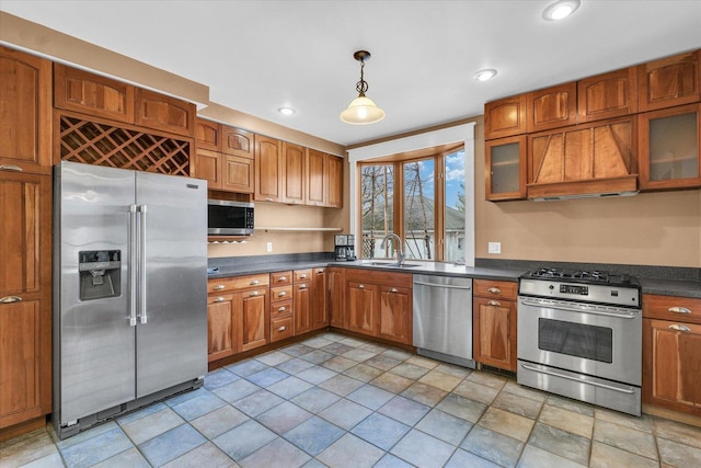 kitchen with dark countertops, custom range hood, appliances with stainless steel finishes, and a sink