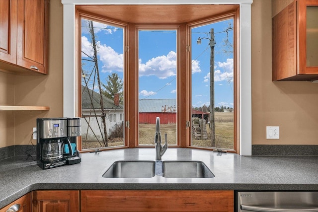 kitchen with a sink, brown cabinets, dark countertops, and dishwasher