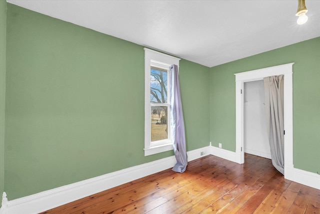 empty room with baseboards and wood-type flooring