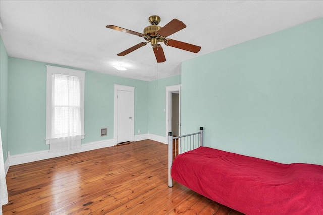 bedroom with a ceiling fan, baseboards, and wood-type flooring